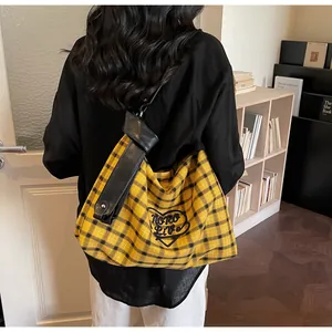 Detail of checkered tote bag with heart logo and black leather strap on model shoulder