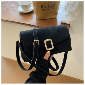Detail of black suede crossbody bag with gold hardware buckle and adjustable strap