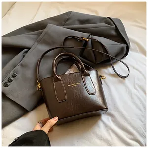 Detail der vintage braunen Ledertasche mit goldenen Beschlägen auf grauem Anzug