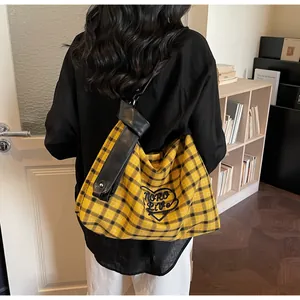 Close-up of yellow plaid tote bag with heart embroidery and black leather strap
