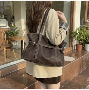 Detail der Vintage-Tote-Bag aus braunem Leder mit weißen Nähten und Gürtelschnallen