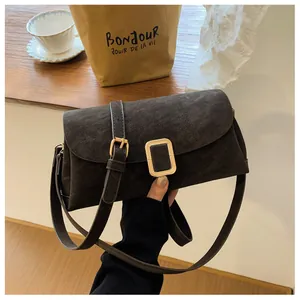 Close-up of a dark brown suede crossbody bag featuring a classic gold rectangular buckle