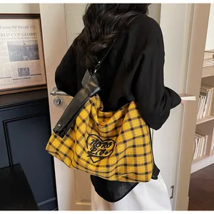 Detail of yellow and black checkered tote bag with heart embroidery and leather strap