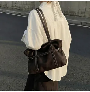 Detail einer dunkelbraunen Ledertasche mit weißen Kontrastnähten und einer Silberschnalle