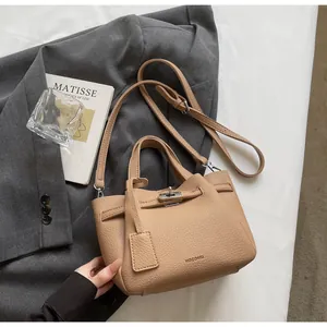Détail du sac seau en cuir beige avec logo HOCOMU et fermeture à fermoir rotatif