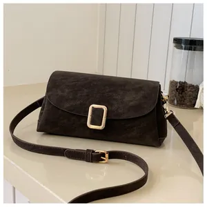 Detail of dark brown matte leather bag with a golden square buckle and adjustable strap