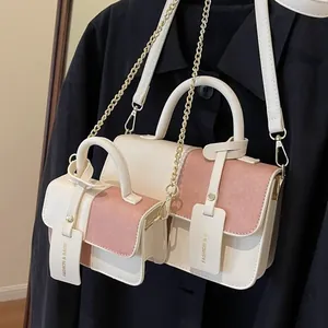 Schicke beige-rosa Umhängetasche im Set mit Goldkette und Griff auf schwarzem Mantel