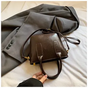 Nahaufnahme einer braunen Vintage-Eimertasche mit Textur auf einem grauen Blazer