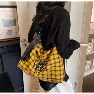 Detail of checkered tote bag featuring a black heart embroidery and stylish knotted strap