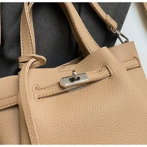 Gros plan sur la texture du cuir grainé et le fermoir métallique du sac seau