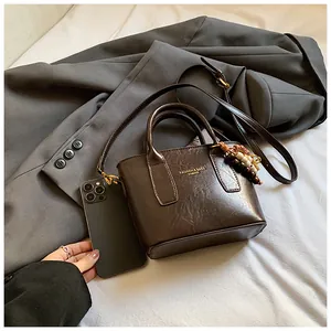 Details einer braunen Vintage-Tasche mit glänzender Textur und Holzperlen-Anhänger