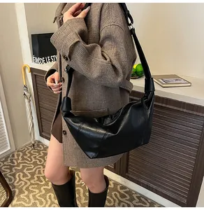 Detail of black pleated faux leather crescent bag with unique knotted wide shoulder strap