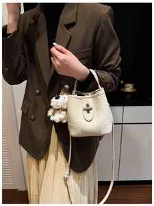 Detail of white bucket bag with lychee leather texture and silver buckle for women