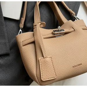 Gros plan sur le sac seau en cuir grainé caramel avec fermoir argenté et texture galet