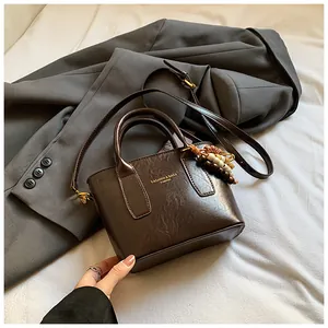 Detailansicht der dunkelbraunen Eimer-Tasche aus Kunstleder mit Holzperlenanhänger