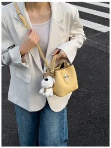 Detailed close-up of yellow pebbled leather bucket bag with cute plush dog pendant charm