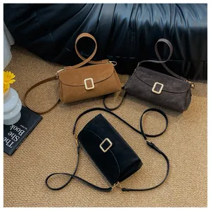 Three minimalist crossbody bags in caramel, grey, and black with gold buckles on a rug