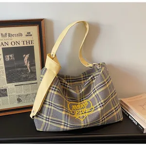 Detail of plaid tote bag featuring yellow heart embroidery and knotted leather strap