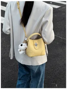 Detail of yellow pebbled leather bucket bag with silver clasp and plush dog charm