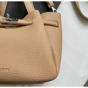 Vue détaillée du cuir beige grainé et du logo COMU embossé sur le sac à main chic