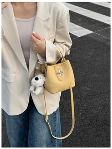Detail of yellow lychee grain leather bucket bag with silver twist lock and puppy charm