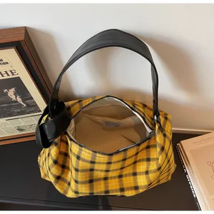 Overhead view of yellow tartan tote interior with black leather strap and knotted detail