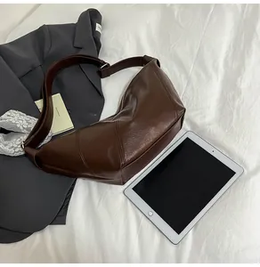 Close-up of deep brown leather crossbody bag with metal zipper on a white fabric background