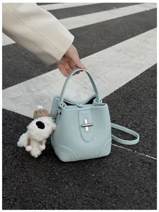 Detail of mint green bucket bag featuring pebble leather and a cute plush dog charm