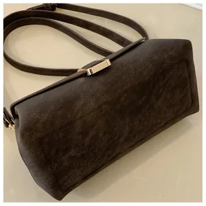 Detail of dark brown matte leather square bag with gold metal snap and sleek texture