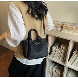 Détail du sac bandoulière en cuir grainé noir avec fermoir métallique et étiquette de marque