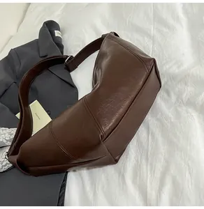 Detailed view of brown PU leather dumpling bag with textured finish and wide shoulder strap