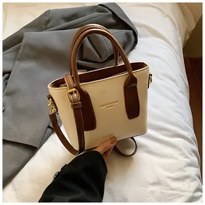 Detail einer schicken Creme-Braun Eimertasche mit goldenen Metallteilen und Riemen