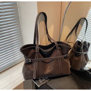 Detail der Vintage-Tragetasche in Kaffeebraun mit verstellbaren Riemen und schmalen Griffen