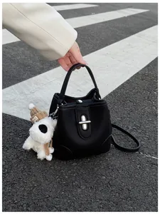 Detail of black lychee grain leather bucket bag with silver twist lock and puppy charm