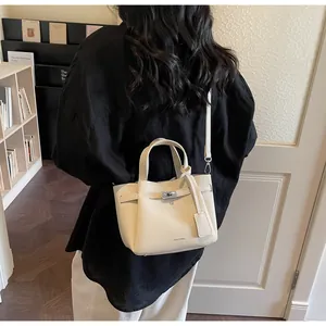Gros plan du sac seau beige en cuir litchi montrant la texture fine et le fermoir argenté