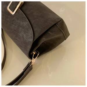 Detail of vintage textured leather shoulder bag with gold square buckle and metal clasp