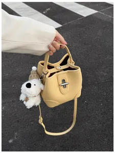 Detail of yellow lychee leather bucket bag featuring silver twist lock and puppy charm