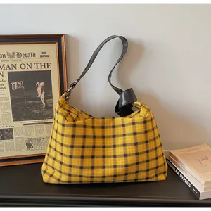Detailed view of yellow and black checkered tote bag with knotted black leather strap