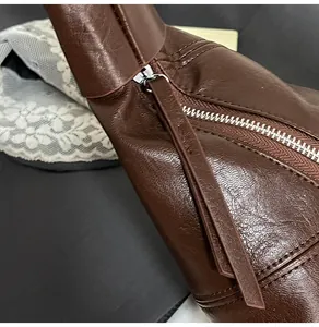 Close-up of brown leather dumpling bag showing silver zipper and fine stitching detail
