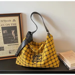 Detail of yellow checkered tote bag with heart embroidery and dark leather strap