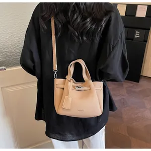Vue détaillée du sac seau en cuir beige à motif litchi avec poignée et fermoir tournant
