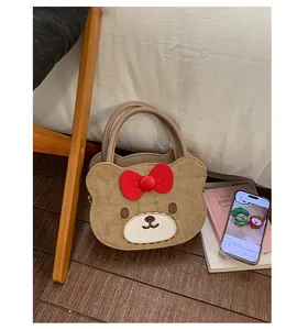 Detail der bärenförmigen braunen Handtasche mit roter Schleife auf dem Holzfußboden