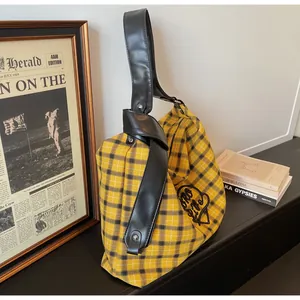 Detailed view of yellow plaid tote bag featuring heart motif and leather straps with rivets