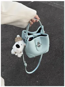 Detail of light blue bucket bag with pebble leather texture and cute dog charm pendant