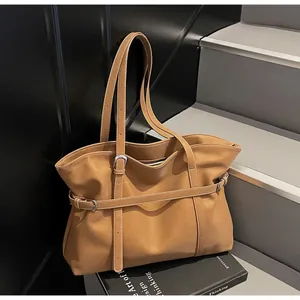 Detailaufnahme der braunen Ledertasche mit Zierriemen und Metallschnallen im Fokus