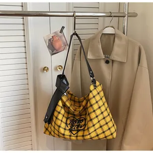Detail of yellow plaid canvas tote bag with black heart print and leather strap