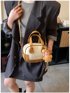 Close-up of cream and brown mini Boston bag with a cute brown plush monkey keychain