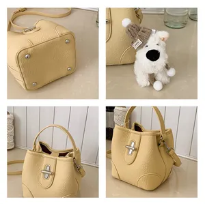 Detail view of cream bucket bag with lychee grain leather and plush dog charm