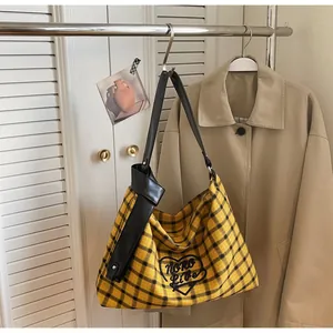 Detailed close-up of yellow plaid tote bag featuring black heart and knot strap