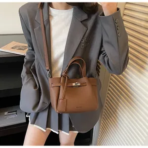 Sac seau en cuir marron avec poignées et bandoulière réglable porté par un mannequin